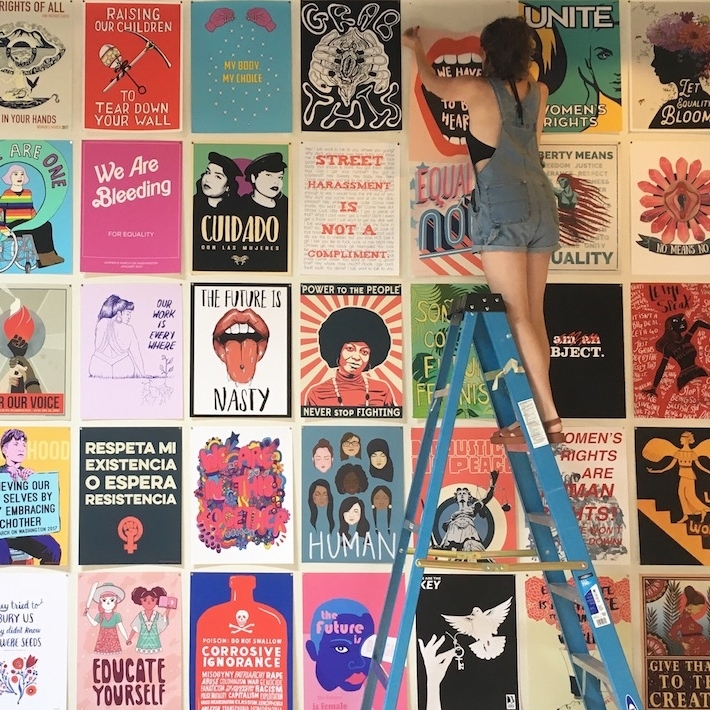 Cleo Barnett on ladder with posters 